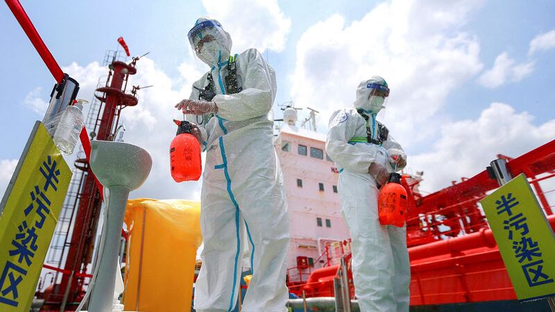 2021 年 8 月 4 日，江苏省南京港，身穿防护服的警察喷雾消毒剂。 （法新社）