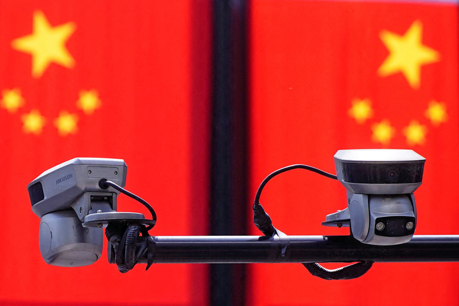 Surveillance cameras in front of Chinese flags at a shopping area in Shanghai, China May 5, 2021.