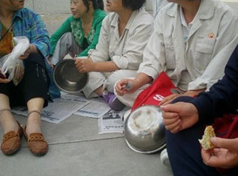 延煉綜合服務公司的員工,手持飯碗,靜坐示威,要求同工同酬。(照片由延煉綜合服務公司員工提供)