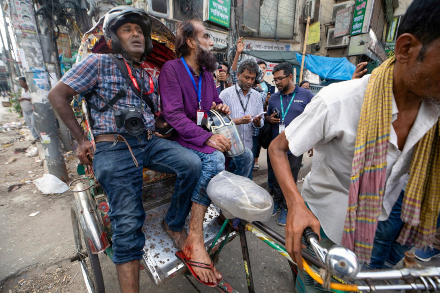 Injured photographers sit on a rickshaw during clashes in Dhaka July 19, 2024. (AFP)