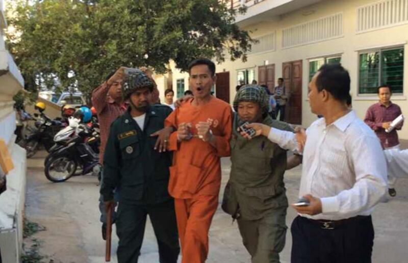 លោក អ៊ុក ពេជ្រសំណាង ក្នុង​សំលៀក​បំពាក់​អ្នក​ទោស​ពណ៌​ទឹកក្រូច ពេល​នាំ​មក​សាលាឧទ្ធរណ៍ នៅ​ថ្ងៃ​ទី ១២ ធ្នូ ២០១៤។ 