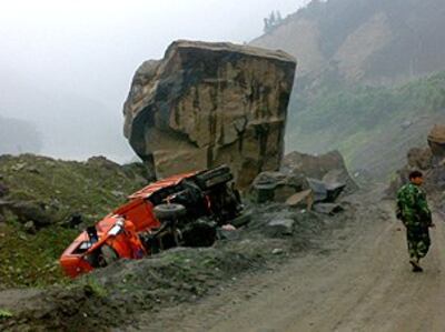 图片：镇外公路的泥石流落下巨石和被压毁的汽车(记者林迪)