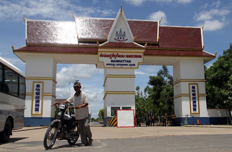 បុរស​ម្នាក់​បណ្ដើរ​ម៉ូតូ​ចេញ​ពី​តំបន់​សេដ្ឋកិច្ច​ពិសេស មេនហាតធេន (Manhattan SEZ) ខេត្ត​ស្វាយរៀង កាល​ពី​ថ្ងៃ​ទី​៥ មិថុនា ឆ្នាំ​២០១៤។