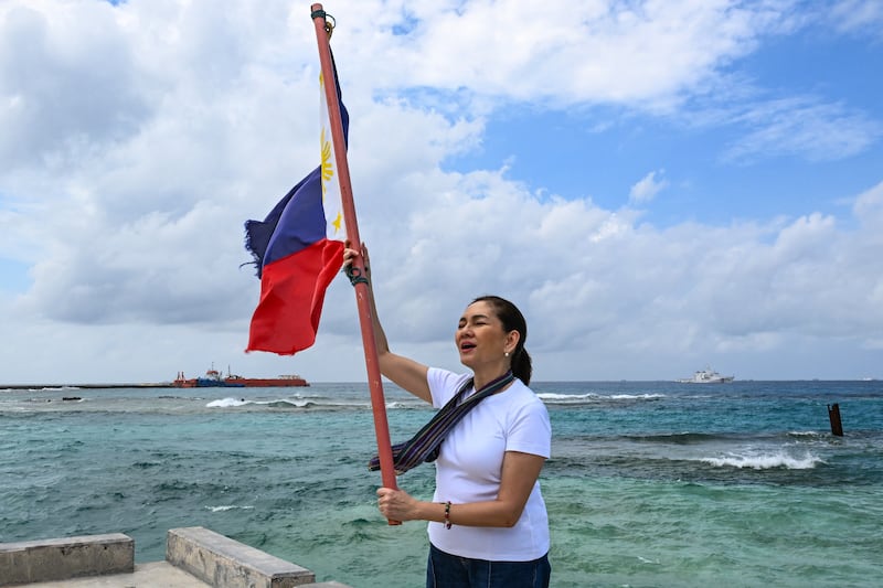 Philippine Senator Risa Hontiveros raises a Philippine flag on Thitu Island in the South China Sea on Feb. 21, 2026.