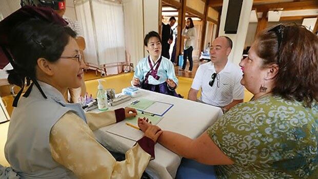 서울 남산 한옥마을에서 열린 '외국인을 위한 한방의료관광 체험행사'에서 관광객들이 조선시대 대장금 복장을 한 전문 한의사로부터 진맥과 상담을 받고 있다. 