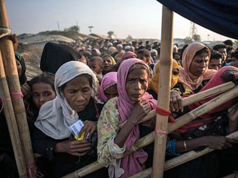 Rohingya Muslim refugees from Myanmar wait to be called to receive food aid of rice, water, and cooking oil in a relief center at the Kutupalong refugee camp southeastern Bangladesh's Cox's Bazar, Nov. 28, 2017.