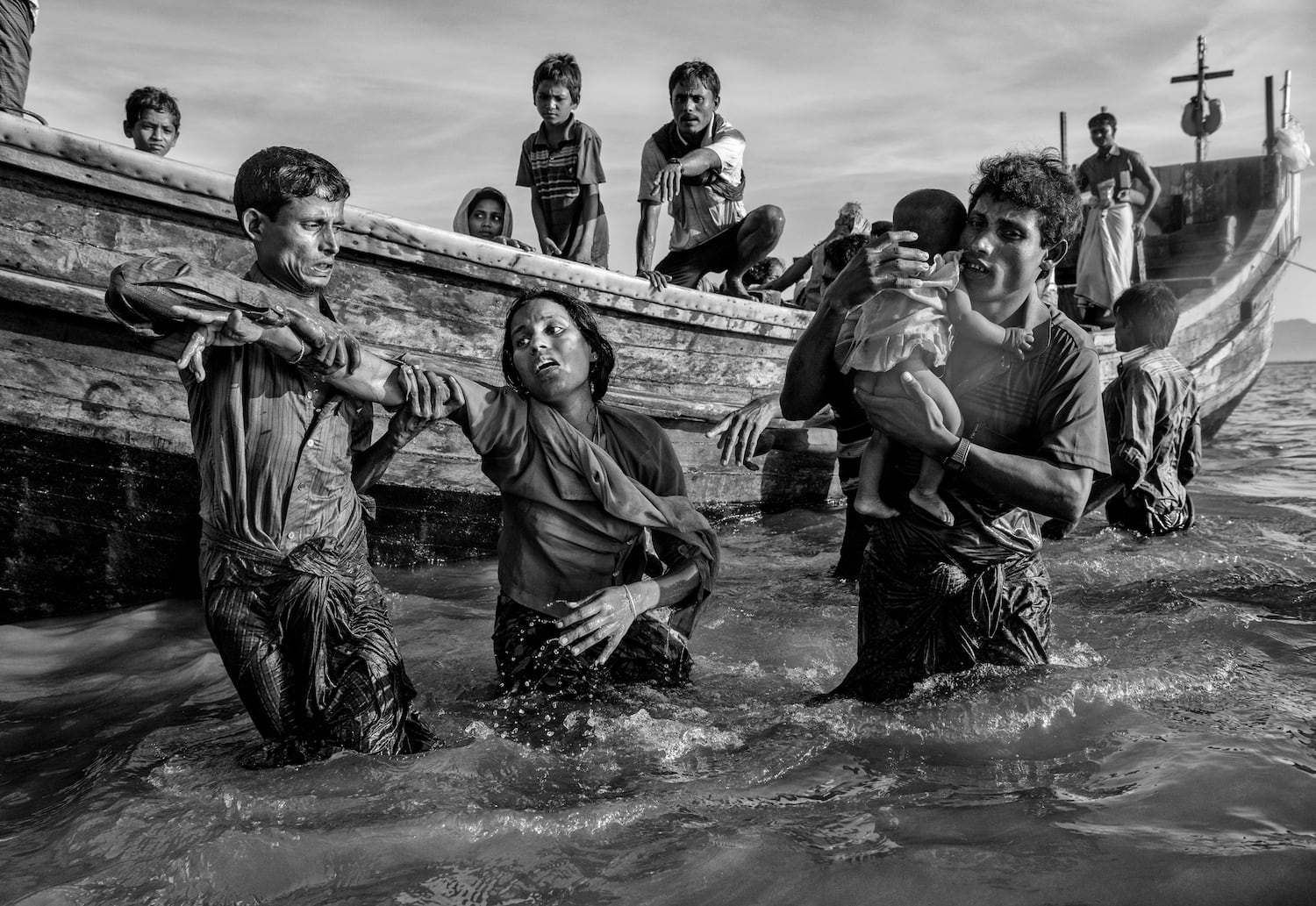 Shikira Arifullah, una refugiada rohingya de 22 años de la aldea de Guddumpara, recibe ayuda desde un barco cuando llega exhausta al lado de Bangladesh del río Naf en Shah Porir Dwip en el lado de Bangladesh del río Naf después de huir de su aldea en Myanmar el 1 de octubre de 2017 en Cox's Bazar, Bangladesh. (Kevin Frayer/Getty Images)