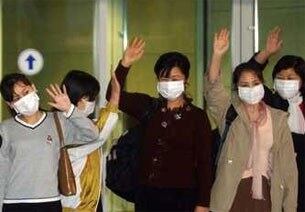 2003년 5월 9일 북한을 탈출해 중국주재 한국대사관에 머물던 여성탈북자 12명이 마스크를 쓴채 새벽 인천공항을 통해 입국, 손을 들어 인사하고 있다.
