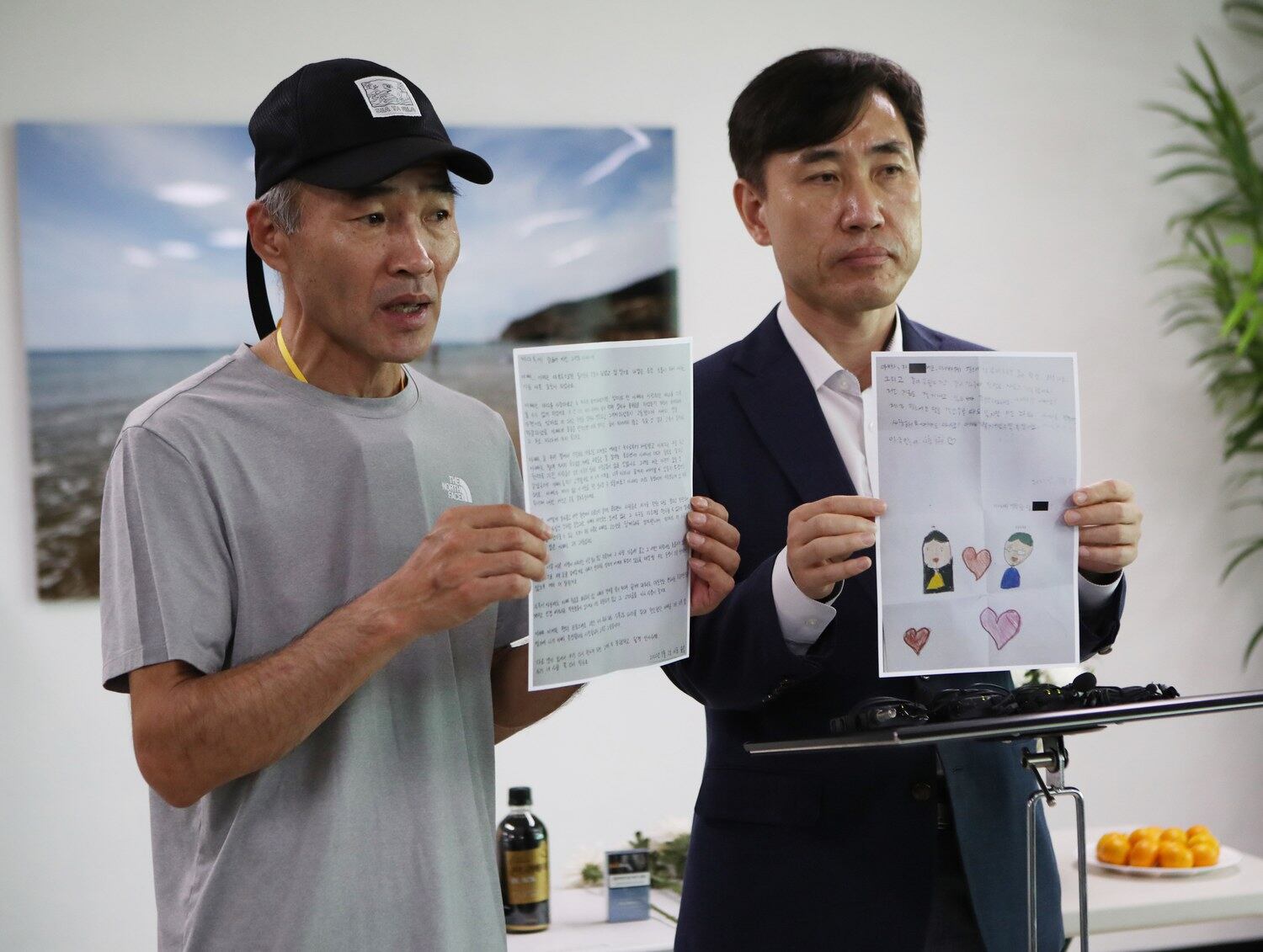2일 인천시 중구 인천항 연안여객터미널 2층에서 열린 '서해 피살 공무원' 이대준(사망 당시 47세)씨의 위령제에서 형 이래진(57)씨와 국민의힘 하태경 의원이 숨진 공무원 자녀들의 편지를 들어보이고 있다.
