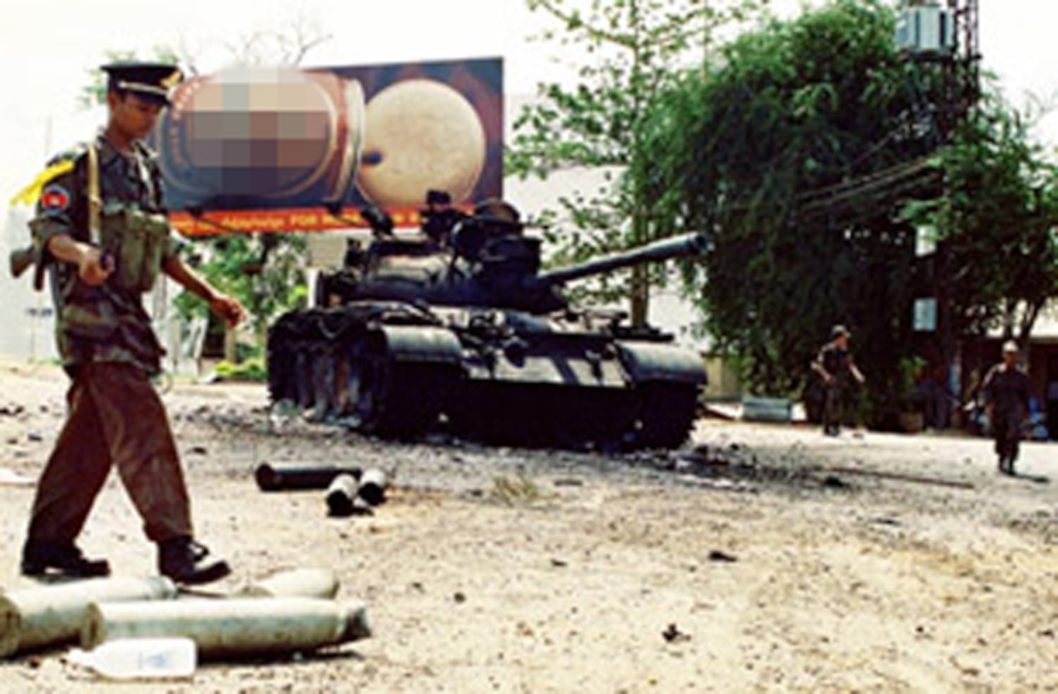 ទាហាន​រដ្ឋាភិបាល​ដើរ​ខាង​មុខ​រថក្រោះ​ឆេះ នៅ​លើ​ដង​ផ្លូវ​មួយ​ក្នុង​រាជធានី​ភ្នំពេញ កាល​ពី​ថ្ងៃ​៧ ខែ​កក្កដា ឆ្នាំ​១៩៩៧។