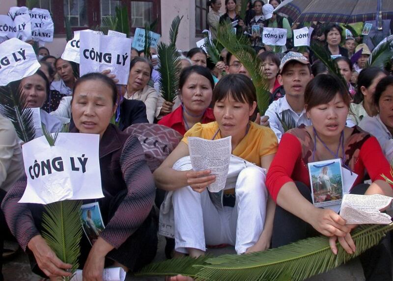 Người Công giáo hát Thánh ca và mang biểu ngữ đòi công lý gần một toà án ở Hà Nội hôm 27/3/2009.