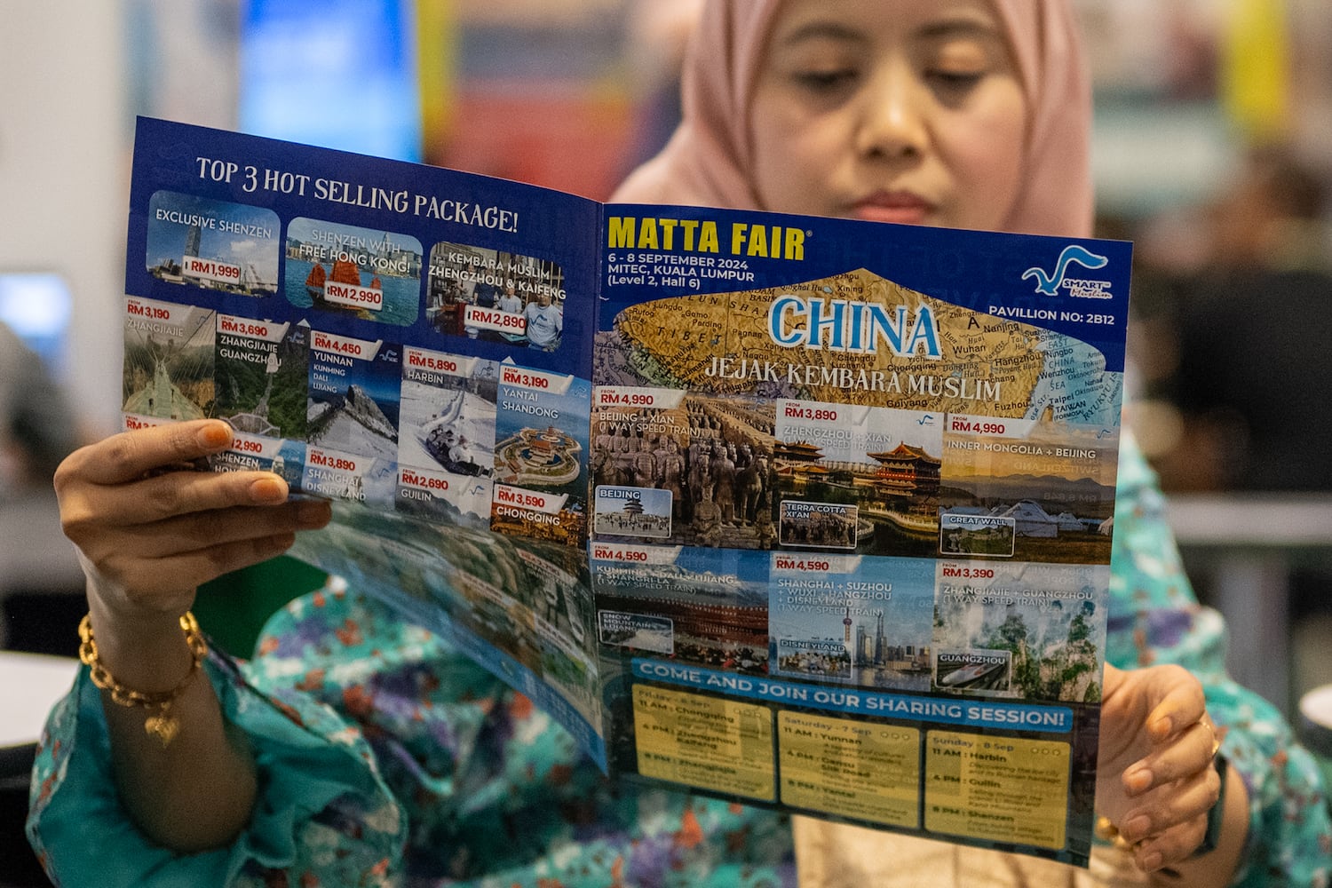 A Muslim woman reads a brochure offering vacation packages to China at a travel agency booth during the Matta Fair 2024 in Kuala Lumpur, Sept. 6, 2024. (S. Mahfuz/BenarNews)