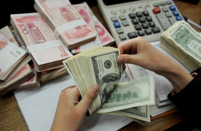 资料图片:工作人员在处理美金和人民币。(AFP)