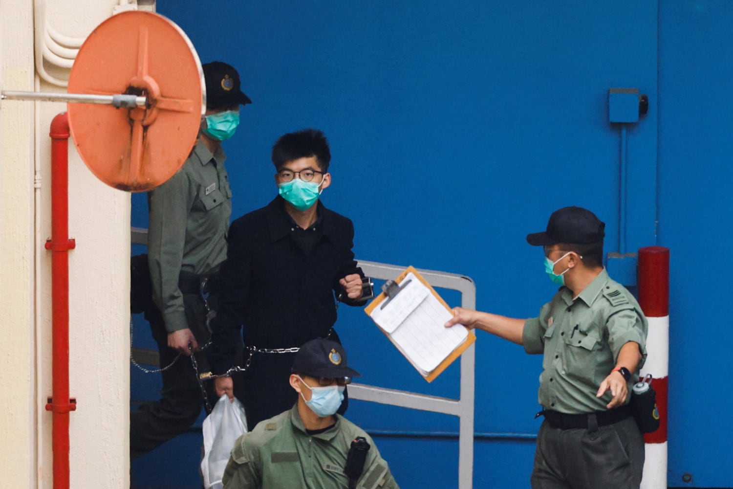 A March 4, 2021, photo shows pro-democracy activist Joshua Wong walking to a prison van to head to court in Hong Kong.