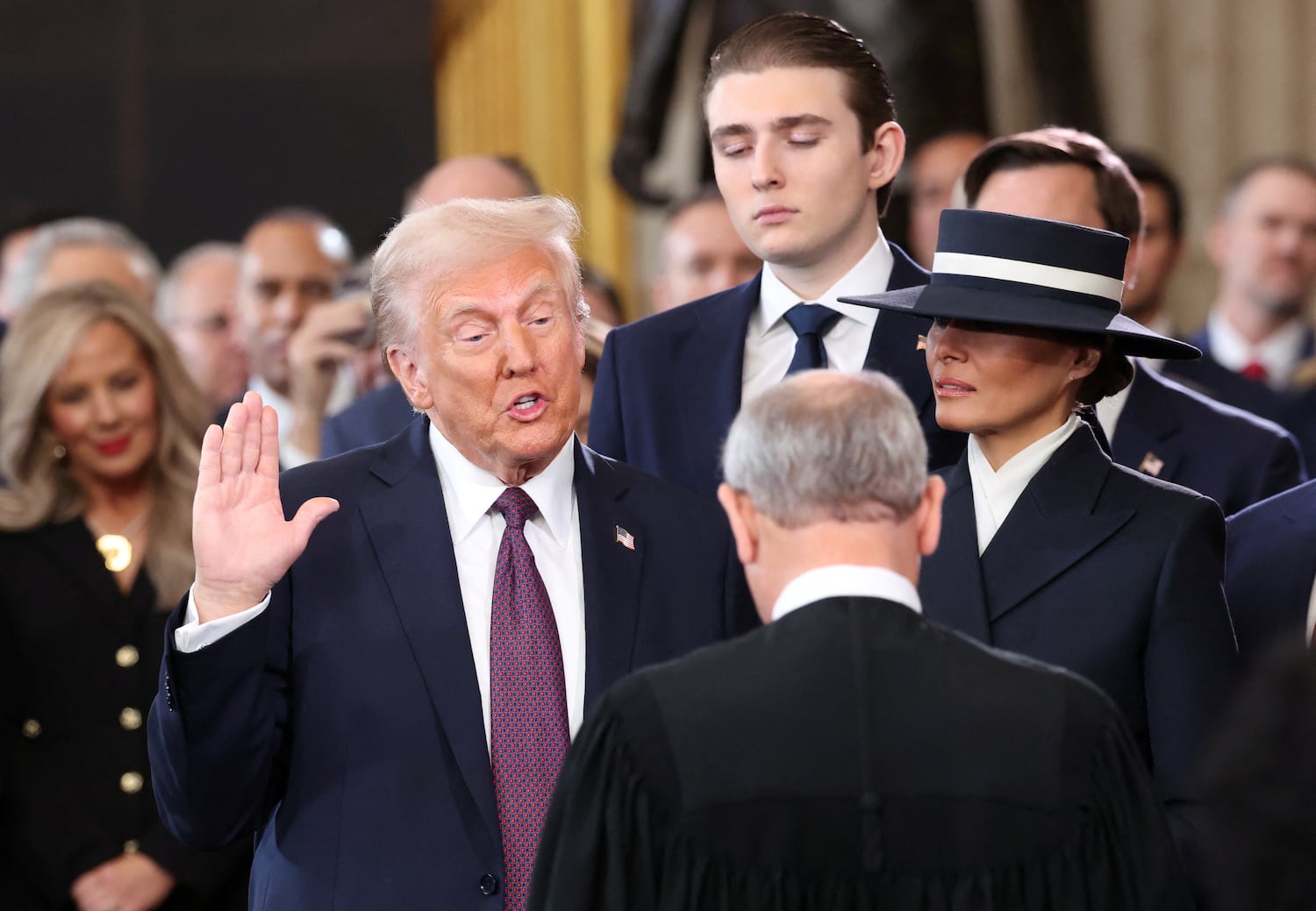 U.S. President Donald Trump takes the oath of office as Barron  and Melania Trump look on at the Rotunda of the U.S. Capitol in Washington, Jan. 20, 2025.
