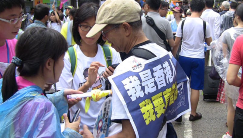 2013年香港七一大遊行上,有市民身掛標語“我是香港人,我要真普選”。(香港市民拍攝並提供)