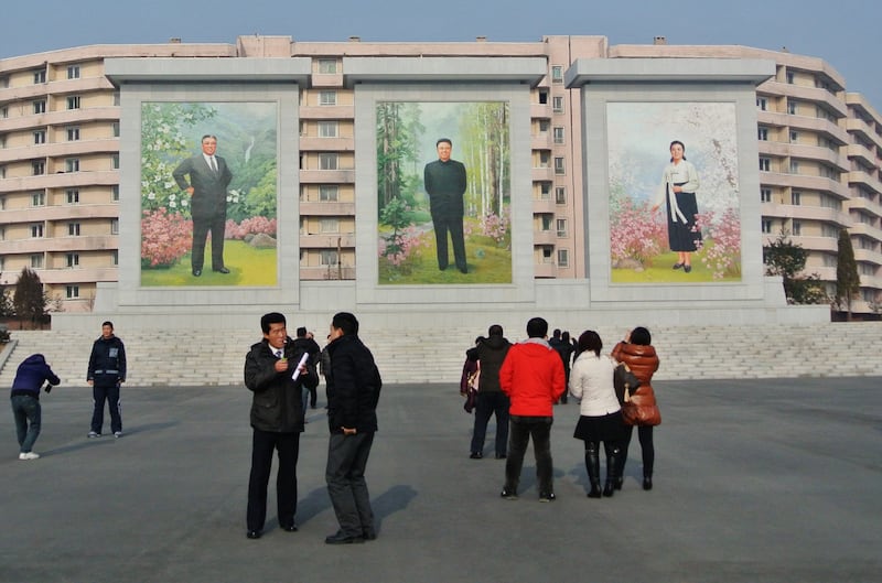 2012년 12월, 중국인들이 신의주에서 김일성(왼쪽)·김정일(가운데) 전 북한 지도자의 벽화를 바라보고 있다.
