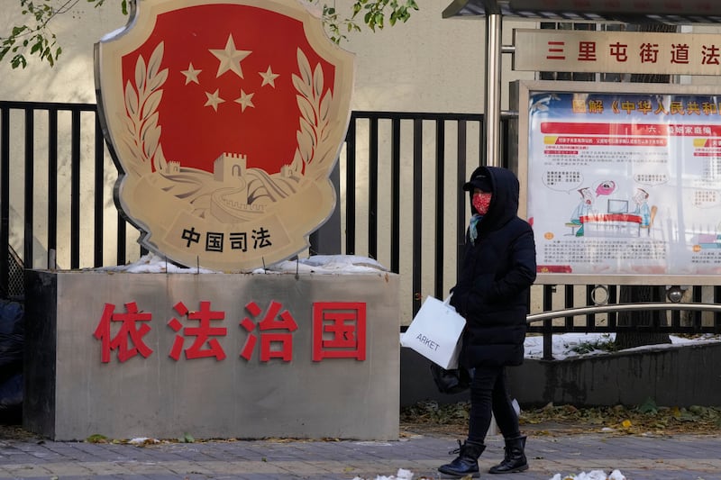 2021年11月8日,一名居民经过北京街头的普法宣传栏。
