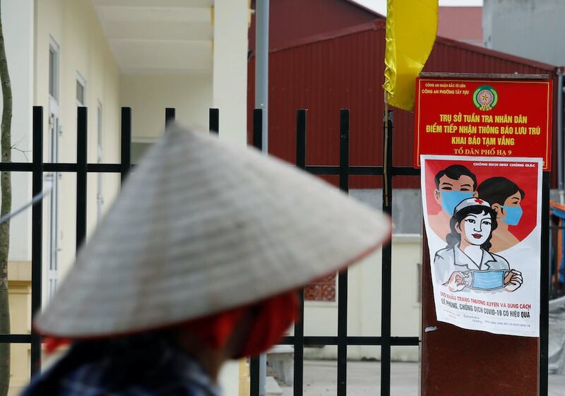 Hình minh hoạ. Một nông dân đạp xe đi qua một áp phích cảnh báo về dịch bệnh COVID-19 ở Hà Nội hôm 22/4/2020