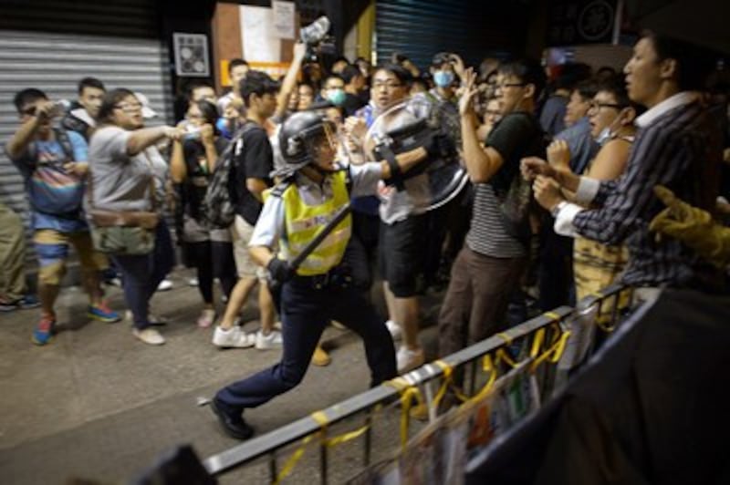 A policeman advances towards pro-democracy protesters as they clash on a street in the Mong Kok area of Hong Kong, Oct. 19, 2014.