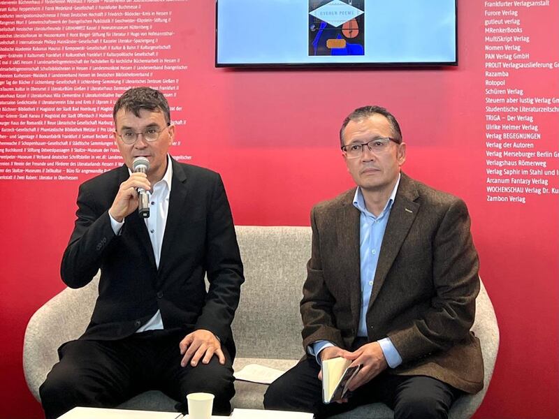 2024 يىللىق فرانكفۇرت كىتاب يەرمەنكىسىدە، گېرمانىيەنىڭ گېسەن ئۇنىۋېرسىتېتى (Giessen University) «ئۇيغۇر مەدەنىيىتى يوقىلىۋاتقاندا شېئىرنىڭ كۈچى» ناملىق يىغىندا سولدىن ئوڭغا دوكتور مىخايېل رەيىنخارد ھېس (Michael Reinhard Hess) بىلەن لوندون ئۇنىۋېرسىتېتى ئافرىقا ۋە شەرقشۇناسلىق ئىنستىتۇتىنىڭ تەتقىقاتچىسى ۋە شائىر ئەزىز ئەيسا ئەلكۈن. 2024-يىلى 17-ئۆكتەبىر، فرانكفۇرت