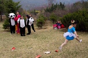 지난해 4월15일 북한 김일성 전 주석의 99회 생일을 기념하기 위해 평양공원에서 열린 공연을 앞두고 북한의 어린 무용수가 팬다곰 복장을 한 소녀들 주위를 뛰어다니고 있다.