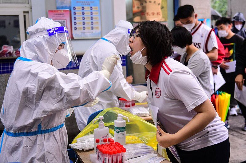 2022 年 6 月 6 日，辽宁省沈阳市，医务人员对高考生进行核酸检测。（法新社）