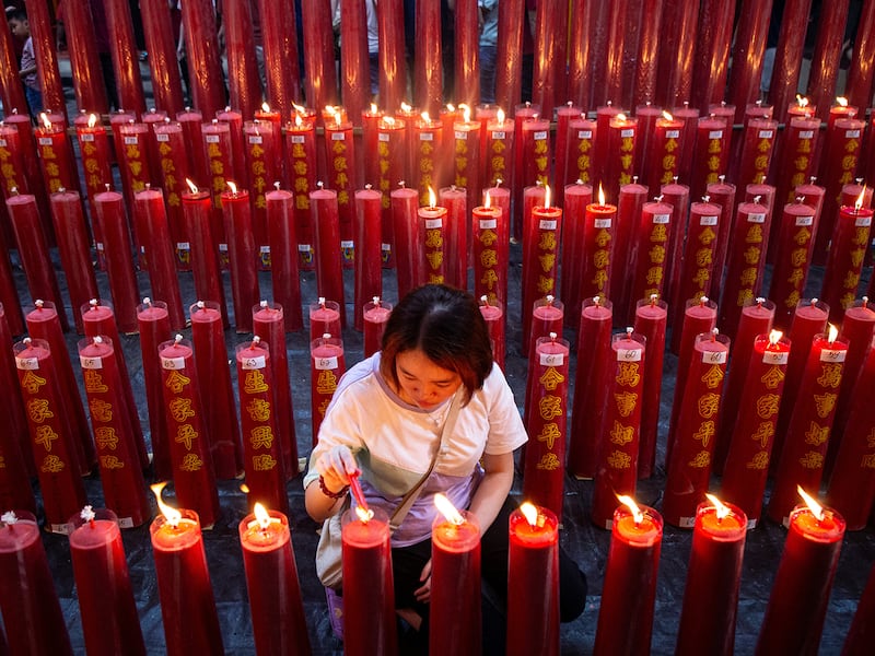 A Chinese woman lights a prayer candle during the Chinese New Year's Eve service at Dhanagun Vihara in Bogor, West Java,  Jan. 28, 2025, on the eve of the Lunar New Year of the Snake.
