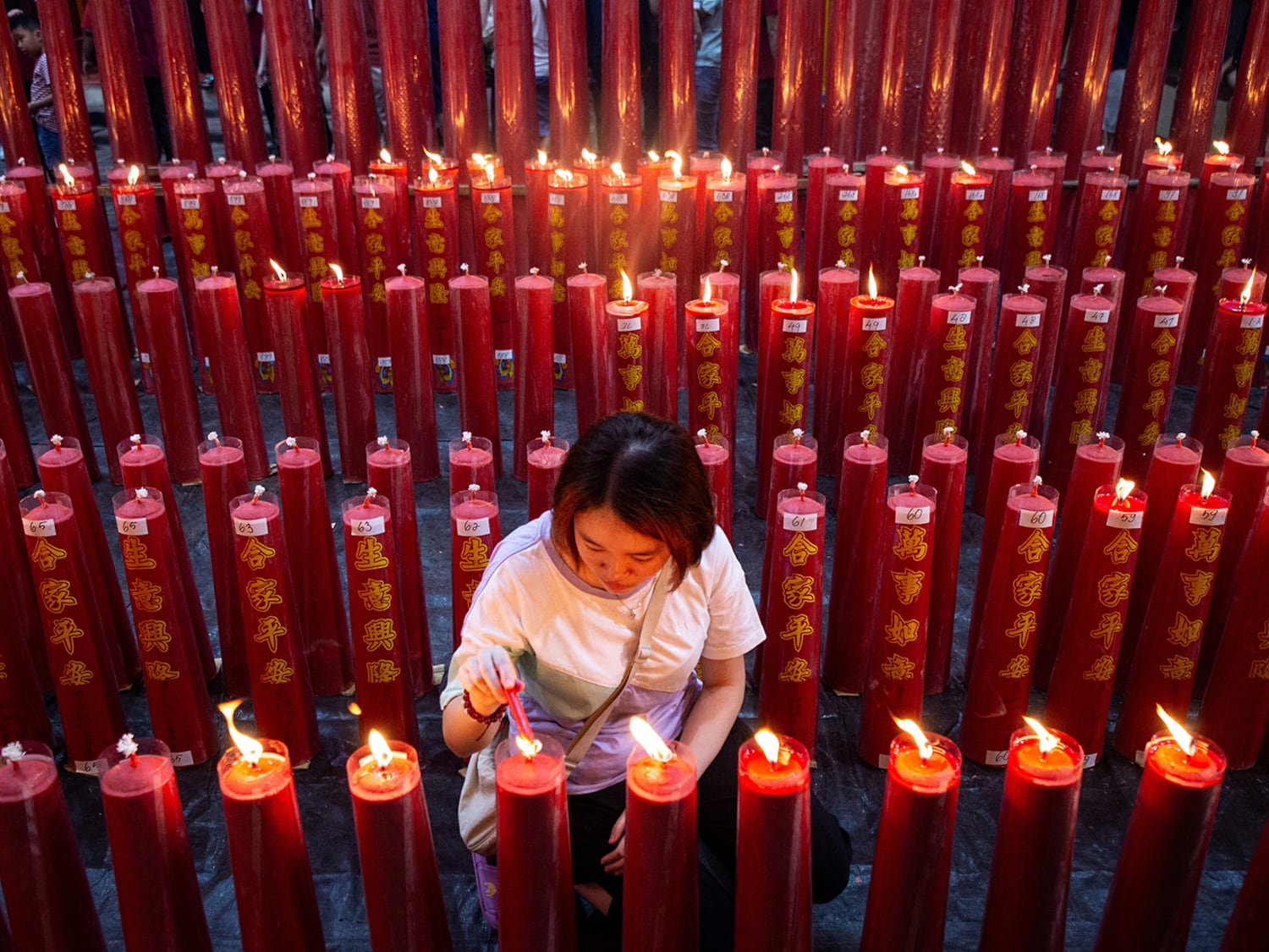 A Chinese woman lights a prayer candle during the Chinese New Year's Eve service at Dhanagun Vihara in Bogor, West Java,  Jan. 28, 2025, on the eve of the Lunar New Year of the Snake.