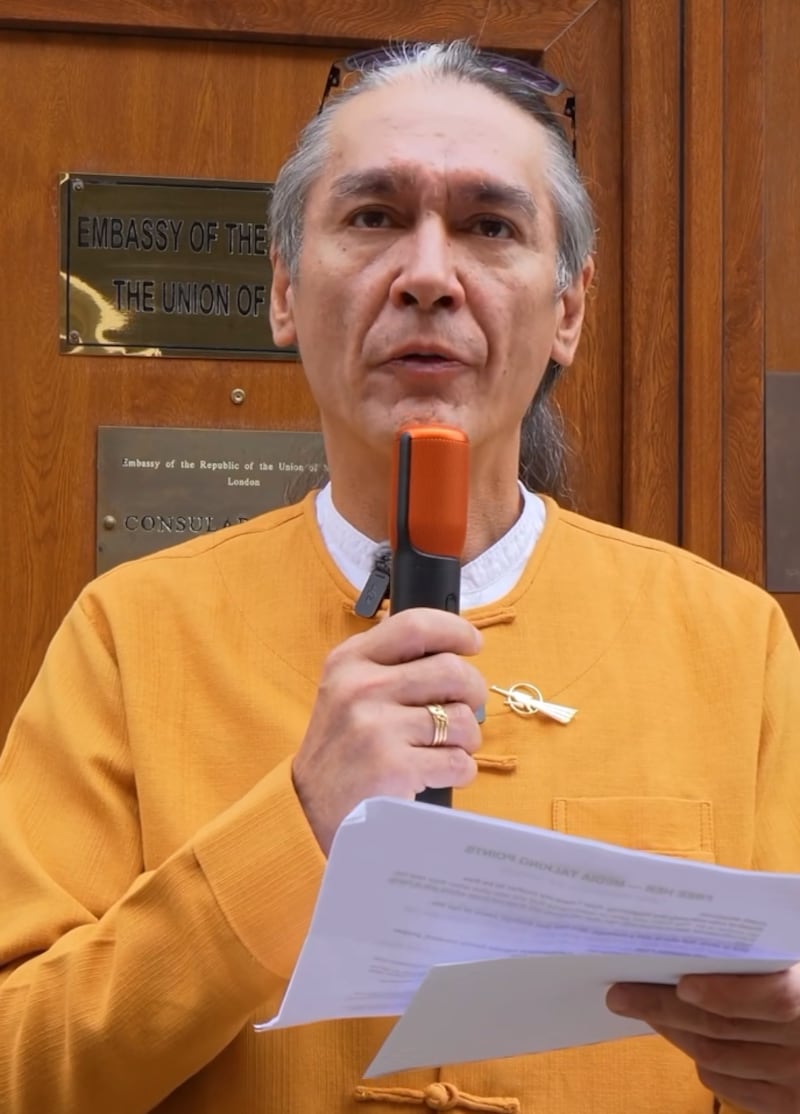 ၂၀၂၆ စက်တင်ဘာ ၂၂ ရက်နေ့က ဗြိတိန်နိုင်ငံ လန်ဒန်မြို့ရှိ မြန်မာသံရုံးရှေ့တွင် မိခင်ဖြစ်သူ ဒေါ်အောင်ဆန်းစုကြည်ပြန်လွှတ်ပေးဖို့ တောင်းဆိုစကားပြောနေသည့် ကိုထိန်လင်း ခေါ် ကင်အဲရစ်အား တွေ့ရပုံ။