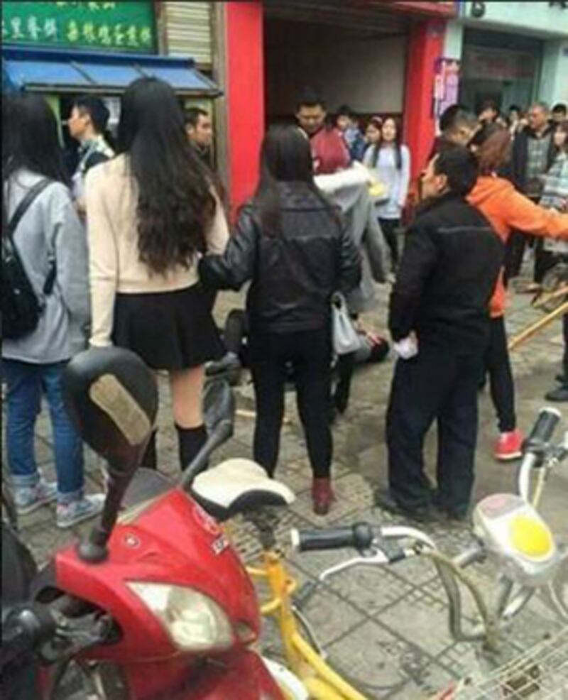 2015年4月9日,小販被城管打趴地上,昏迷不醒,大批途人包圍。(目擊學生提供)