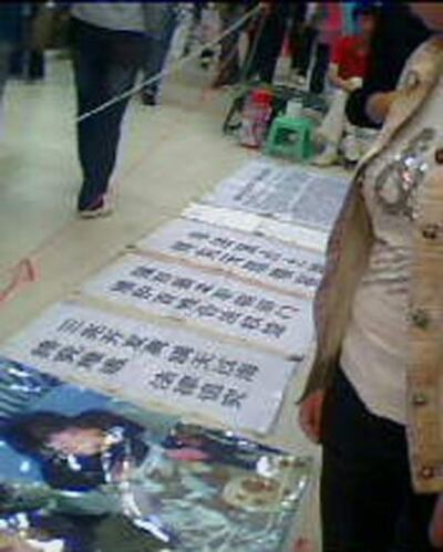 图片：杨白云兄弟将被打伤的照片及资料摆放在被罢占的商铺前。(志愿者)