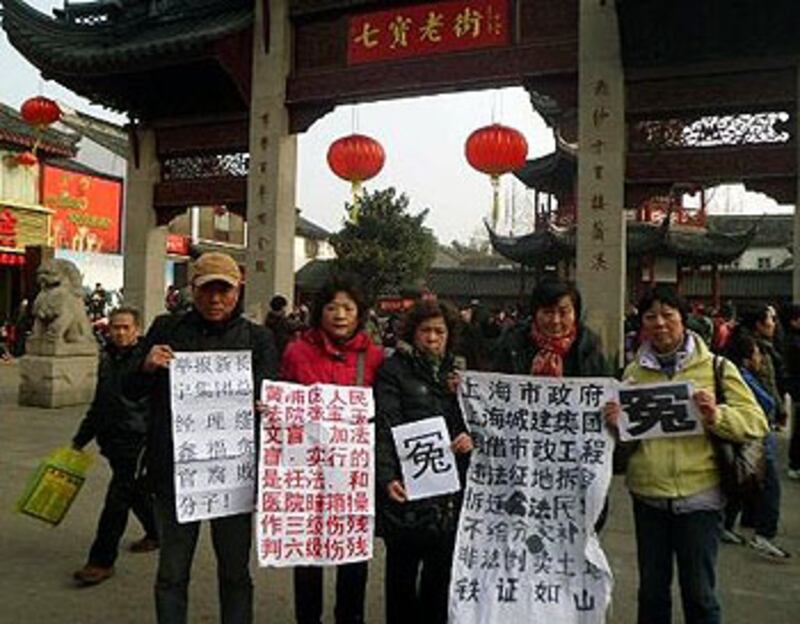 2013年2月13日,上海七名訪民包括吳玉芬、孔令珍、石萍、嚴燕文等人,大年初四手持狀紙和維權標語到當地著名景點七寶鎮維權拍照。(參與訪民提供)