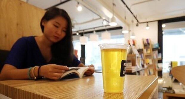 퇴근길 직장인이 맥주 한잔을 기울이며 책을 읽고 있다.