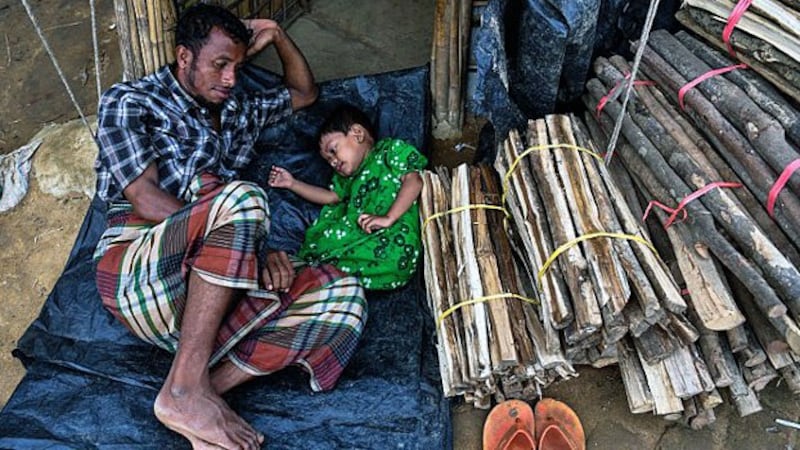 A Rohingya refugee man from Myanmar plays with his daughter by the entrance of their tent at the Kutupalong camp in Ukhia sub-district, Cox's Bazar, in southeastern Bangladesh, Aug. 13, 2018.