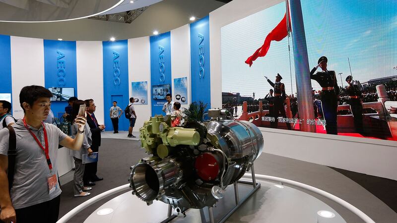 北京中国航空博览会上，参观者在观看展示中国升旗仪式的屏幕附近的飞机零部件。（美联社）
