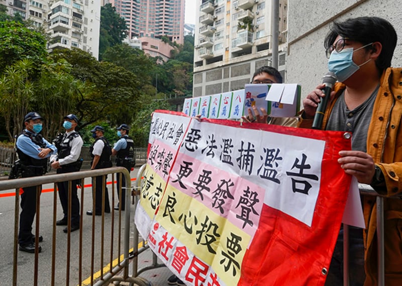 民主派抗議者在投票站外拉布條呼籲選民「良心投票」。(美聯社)