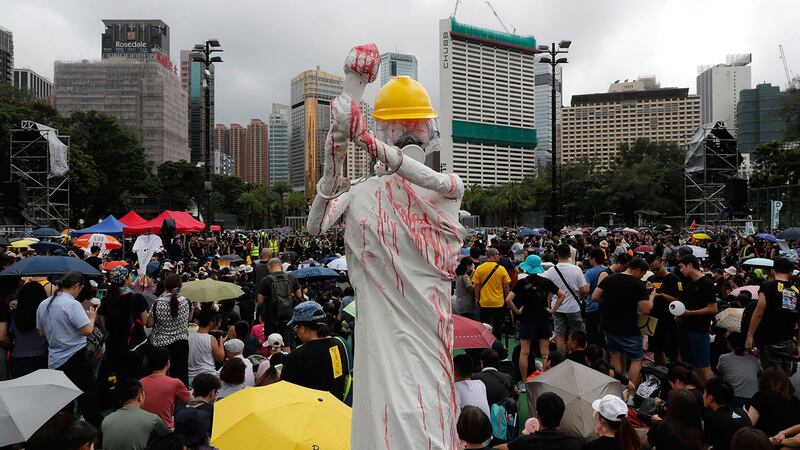 2019年8月18日,香港反送中集会上,展示了民主女神的复制品,戴着安全帽,防毒面具,手铐,并用红色液体覆盖。(美联社)