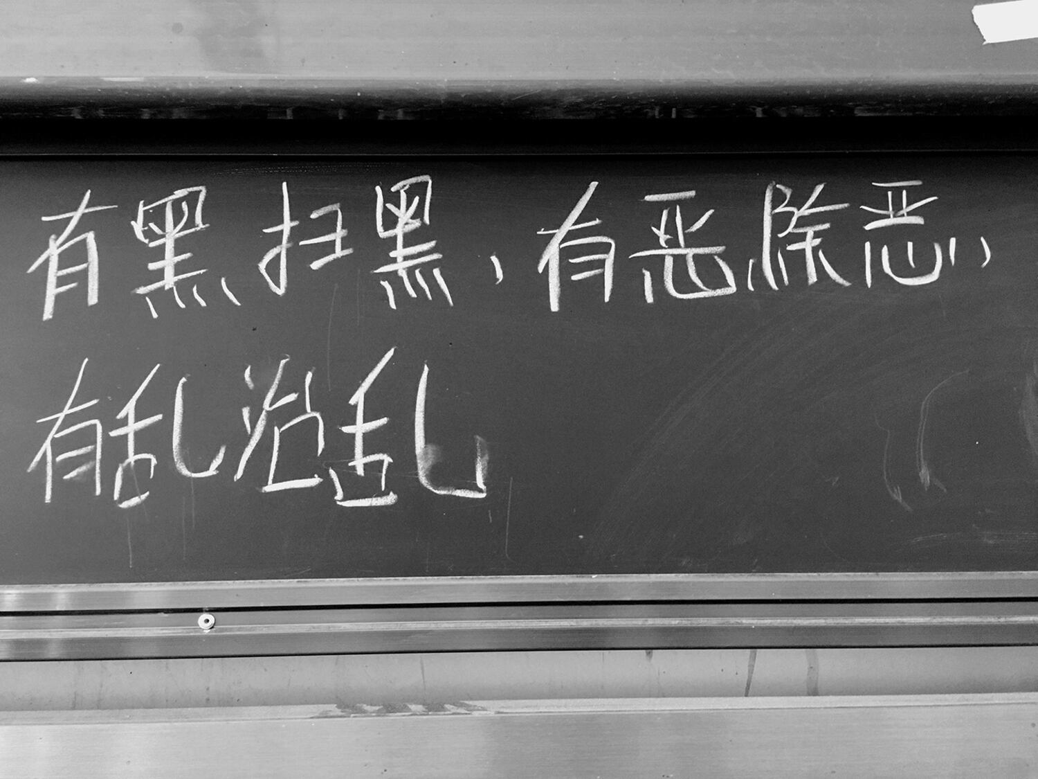 The slogan 'Where darkness arises, sweep it away; where evil arises, eliminate it; where chaos arises, govern it' is written on a blackboard at Paxiang Central Primary School during a 2019 trip to northwestern China's Xinjiang region by a Taiwanese delegation that included high-school students.