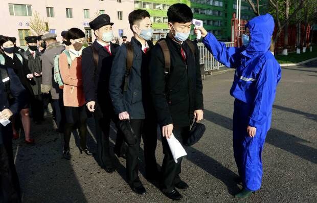 마스크를 쓴 김책공대 재학생들이 코로나19 발생 이후 첫 등교하는 날 학교 앞에서 체온을 재고 있다.