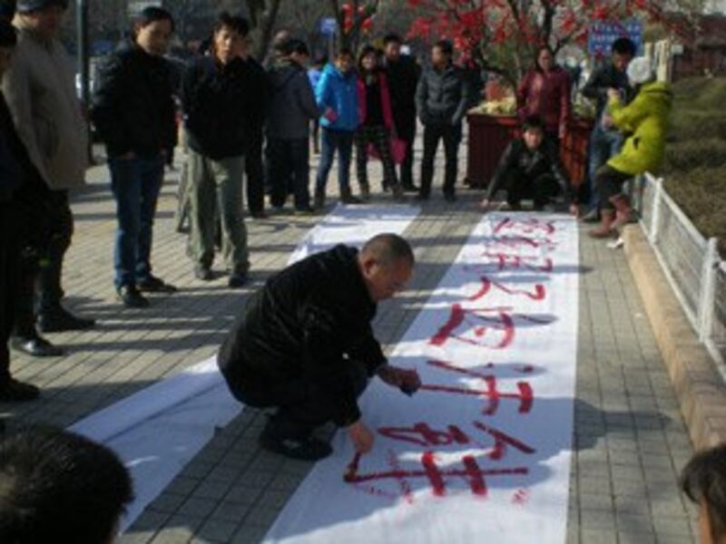 图片： 四川农民工在陕西省政府门前写横幅追讨工钱。 （马晓明提供/记者乔龙）