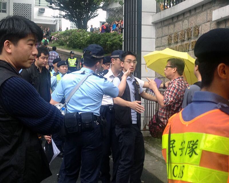 2015年3月15日,一名市民(右二)在禮賓府門外過安檢時,張開印有“雨傘世代”字樣的黃傘,被警方截停查問。(任吉攝)