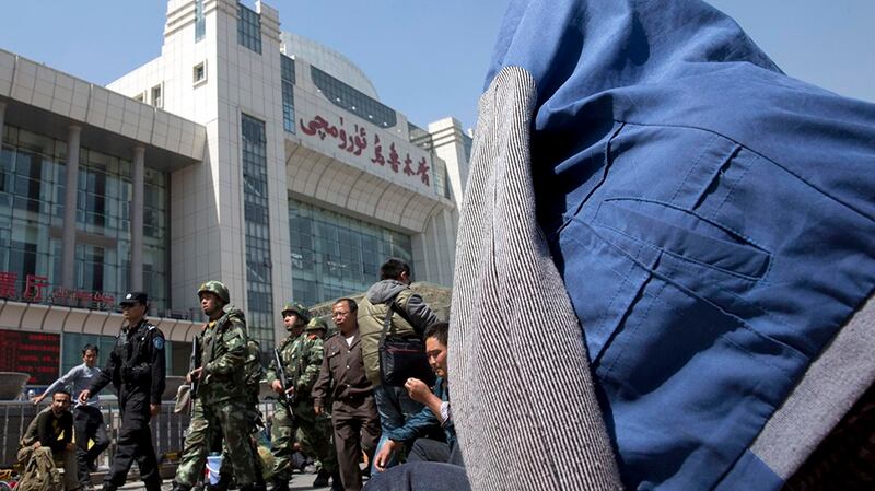 Chinese paramilitary police march past the Urumqi South Railway Station in Urumqi, in a file photo. Credit: AP Photo
