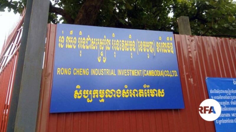 ស្លាកសញ្ញានៅជាប់របងក្រុមហ៊ុនចិន រ៉ុង ឆេង ដែលជាទីតាំងសិប្បកម្មលាងសំអាតរ៉ែមាស។ រូបថតនៅថ្ងៃទី៨ កញ្ញា ២០១៨។