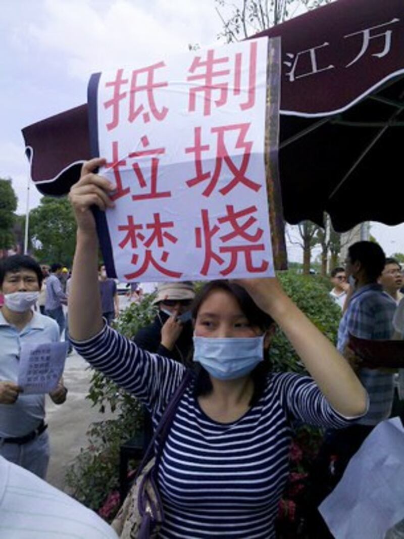 图片：抗议者戴口罩，举标语。（中国茉莉花革命网站）