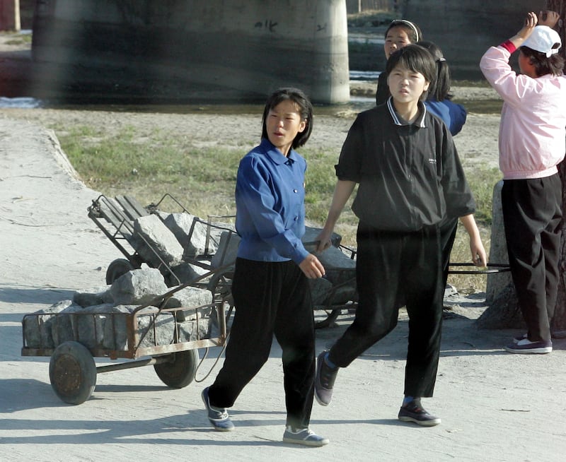 2004년 10월, 북한 개성에서 학생들이 철도 건설 현장으로 돌을 나르고 있는 모습.