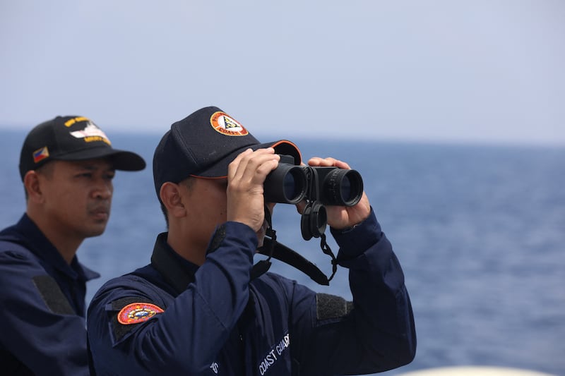 In this file photo, a Philippine Coast Guard personnel looks through binoculars while conducting a resupply mission for troops stationed at a grounded warship in the South China Sea, Oct. 4, 2023.