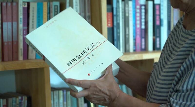 戴晴从书架上抽出一本《阎明复回忆录》，勾起对往事的回忆。（RFA）
