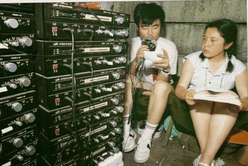 1989年5月24日，两名学生在天安门广场广播站播音。各地消息源源不断送达这个设置在天安门广场的广播站，这里日益成为信息中心和广场学运协调中心。（Public Domain）