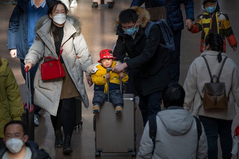 A man pushes a child riding on a suitcase at Beijing West Railway Station in Beijing, Jan. 18, 2023.
